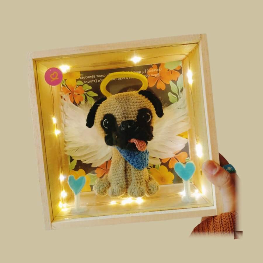 Caja de madera iluminada con la figura tejida de un pug con alas y halo
